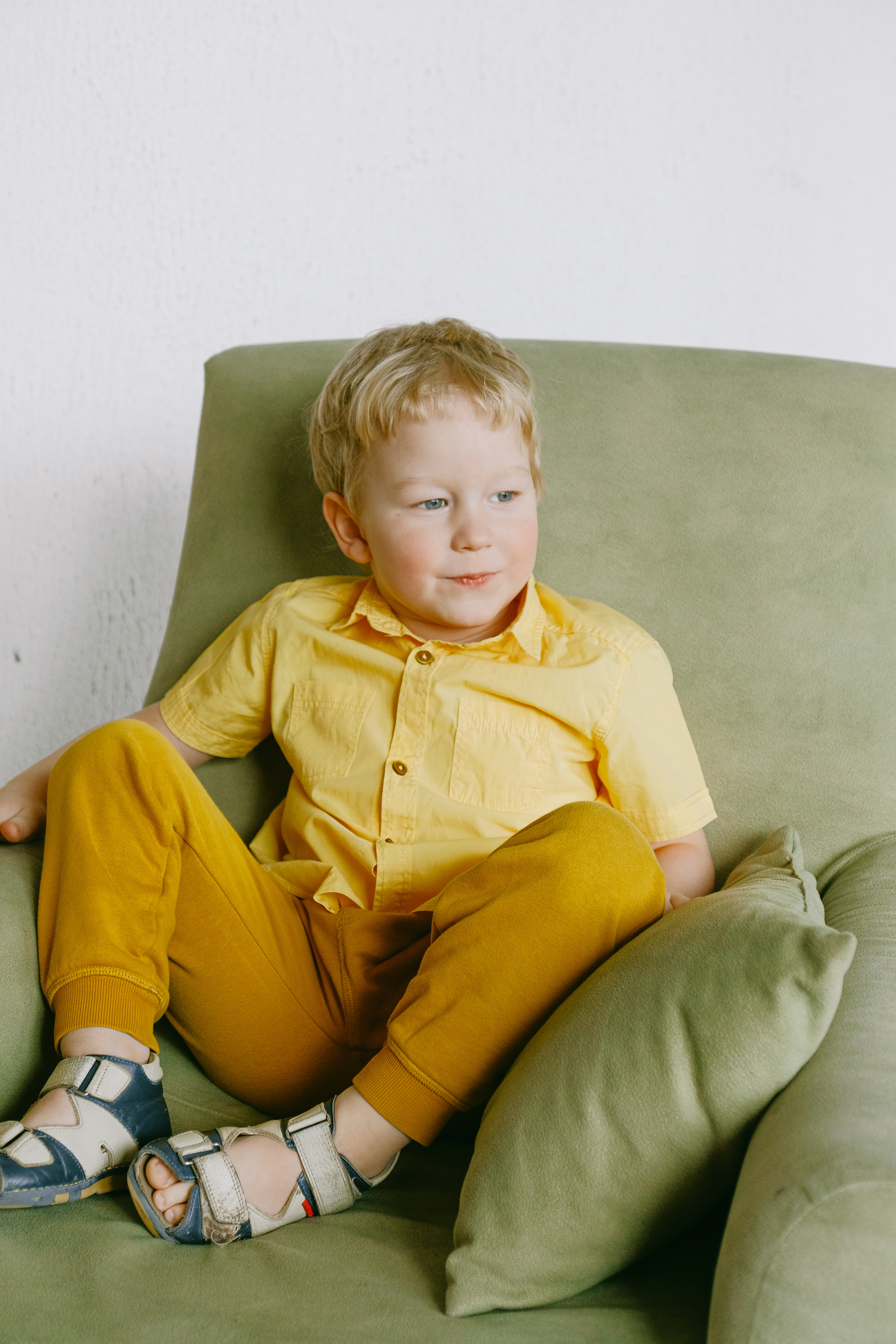 Boy in Yellow Button Up Shirt Sitting on Gray Sofa Chair